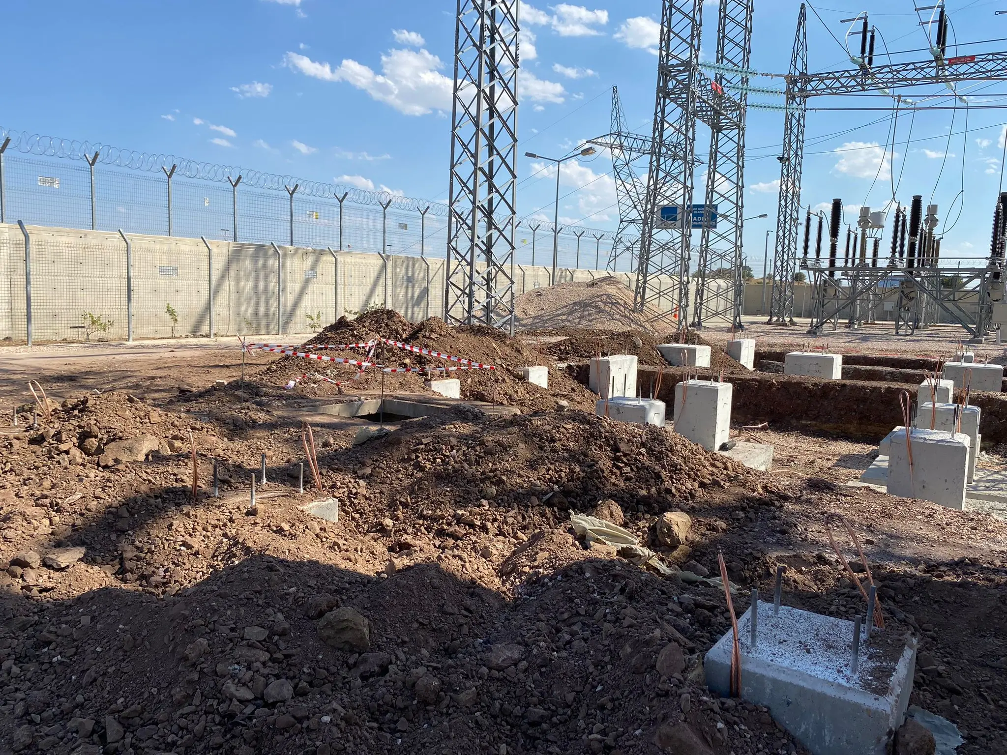 Çevre güvenlik duvarı önünde kazı çalışması süren beton ekipman temel sahası